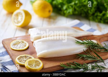 Frisches, rohes Tintenfischfilet mit Zitronen auf einem Holztisch selektiver Fokus. Stockfoto