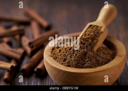 Zimtpulver in einer Holzschale auf einem dunklen Holztisch. Stockfoto