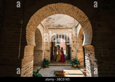 Drei Frauen in traditioneller spanischer Kleidung stehen unter einem Bogen im Alcázar von Jerez de la Frontera, Andalucía, Spanien Stockfoto