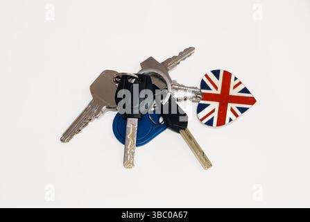 Eine Sammlung von Schlüsseln mit verschiedenen Köpfen, die an einem Schlüsselanhänger befestigt sind, mit einem herzförmigen Anhänger von Union Jack. Die Schlüssel und der Schlüsselanhänger liegen auf einem weißen Hintergru Stockfoto