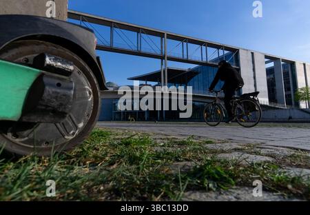 Nahaufnahme eines E-Scooters und eines vorbeifahrenden Radfahrers vor der Marie-Elisabeth-Lüders-Brücke im Zentrum Berlins. Stockfoto