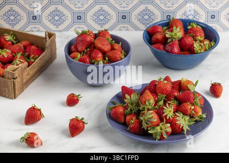 Frische Erdbeeren in blauem Geschirr auf einem Marmorteller Stockfoto