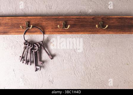 Ein Haufen alter Metallschlüssel auf dem Ring, die an Haken hängen, Holzbügel Stockfoto