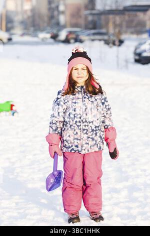 Mädchen mit Schaufel auf dem Schnee im Winter Park Stockfoto