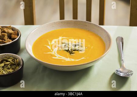 Warme, frisch zubereitete Suppe serviert mit saurer Sahne und Kürbiskernen. Kürbiscremesuppe auf leichten Servietten, vegetarische Delikatessen. Perfektes Gericht für CO Stockfoto