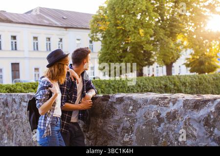 Ein junger, hübscher Mann, der eine reizende Frau hält und auf interessante Sehenswürdigkeiten zeigt, die beide in der Nähe der mittelalterlichen Burg stehen. Konzept für Familienreisen Stockfoto