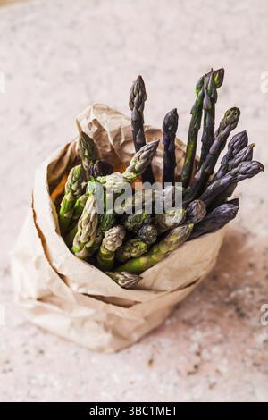 Bündel von frischen, grünen und violetten Spargel spears Schließen in Papiertüte auf dem Tisch Stockfoto
