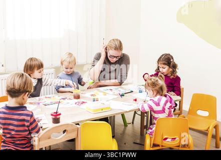 Kinder malen Mit Pinsel und Wasserfarben auf Papier in den Kindergarten Stockfoto
