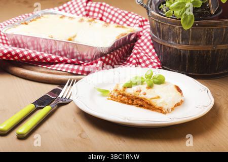 Ein Stück Lasagne Bolognese mit Basilikumblättern auf einer weißen Platte Stockfoto