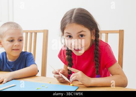 Bruder und Schwester haben Spaß zusammen mit farbenfroher Modelliermasse zu Hause. Kinder spielen mit Plastilin oder Teig Stockfoto