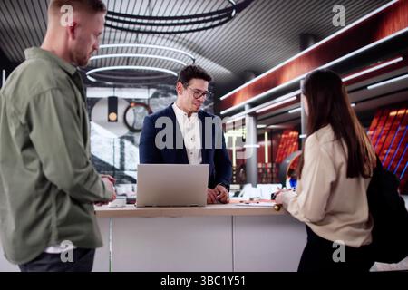 Beim Einchecken an der Hotelrezeption trifft sich Ein Paar auf den Concierge. Stockfoto
