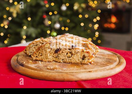 Christstollen. Traditionelle süße Früchte Brot mit Puderzucker bestreuen. Weihnachten Urlaub Tabelle mit Stollen. Weihnachtsbaum und Kamin auf dem Zimmer Stockfoto