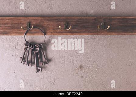 Ein Haufen alter Metallschlüssel auf dem Ring, die an Haken hängen, Holzbügel Stockfoto