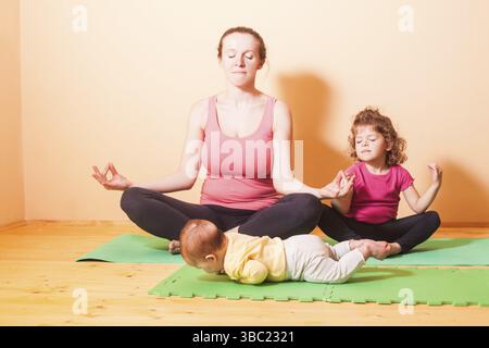 Mutter mit zwei Kindern Yoga Übungen in Home Stockfoto