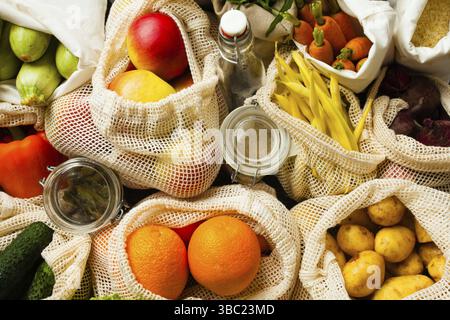 Gemüse und Obst in Textilbeuteln, Glasgläser mit Bohnen und Öl als Hintergrund. Lebensmitteleinkäufe ohne Verschwendung Stockfoto