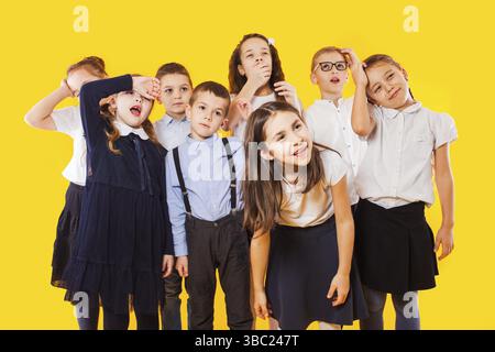 Schülerinnen mit Rucksäcken und gekreuzten Händen stehen auf gelbem Hintergrund. Die Schüler sind bereit zur Schule zu gehen. Wieder-in-die-Schule-Konzept Stockfoto