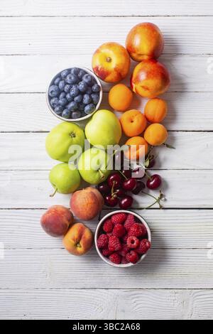 Von oben auf eine Reihe von verschiedenen traditionellen Früchten verteilt auf einer weißen Holzoberfläche Stockfoto