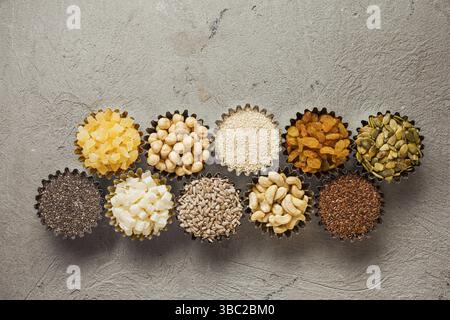 Verschiedene Nüsse und trockene Früchte in Schüsseln auf grauem Hintergrund, Draufsicht Stockfoto