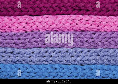 Flache horizontale Reihen aus blau-rosa geflochtenem Material. Makrobild gestrickter grober Fäden Stockfoto