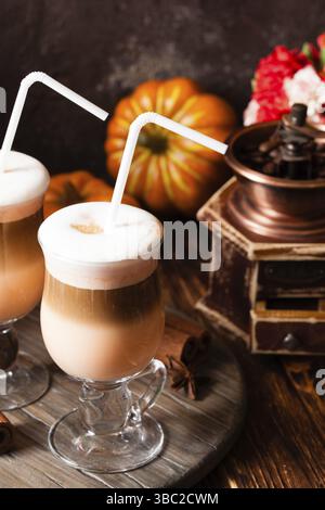 Zwei Gläser Kürbis würzig Latte mit Sahne und Zimt auf einem Holzständer Stockfoto