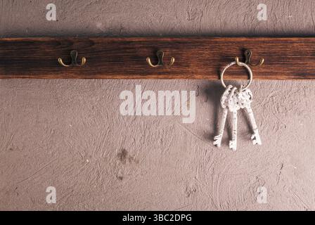 Ein Haufen alter Metallschlüssel auf dem Ring, die an Haken hängen, Holzbügel Stockfoto