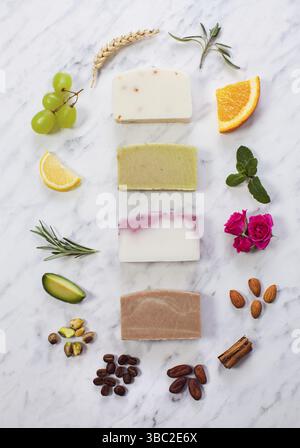 Draufsicht auf Scheiben ökologischer, hausgemachter Seife im Kreis verschiedener natürlicher Inhaltsstoffe, die Bestandteile von Bio-Kosmetik sind Stockfoto