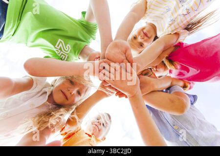 Kinder Hände halten fest zusammen im Kreis einer Verlegung auf eine andere auf einem weißen Hintergrund, Ansicht von unten. Teamwork Konzept Stockfoto