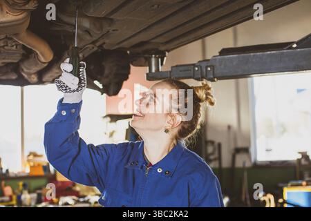 Eine Mechanikerin repariert ein Auto in der Garage. Autoreparaturwerkstatt Stockfoto