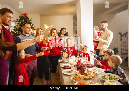 Glückliche Familie mit Sparklern, die Spaß auf der Dinnerparty zu Hause haben. Weihnachtsfeier Stockfoto