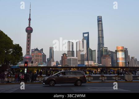 Shanghai, China - 1. April 2025: Blick auf die Skyline von Pudong mit Shanghai Tower und Oriental Pearl von der Nanjing Road bei Sonnenuntergang mit Menschen und Autos Stockfoto