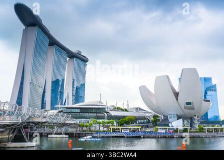 Singapur, Singapur - 4. April 2025: Das ikonische ArtScience Museum und der Marina Bay Sands Complex, verbunden durch die Fußgängerbrücke Helix Bridge, unter Laune Stockfoto