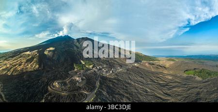 Luftpanoramablick auf den Vulkan Mount Etna in Sizilien, Italien. Aktive Vulkanlandschaft mit alten Lavafeldern und Rauch aus den Kratern, Drohnenfotografie. Stockfoto