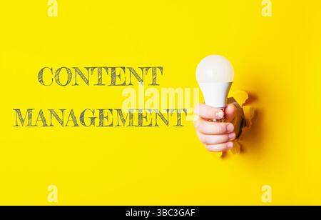 Person, die eine Glühbirne hält, hinter der das Wort Content Management steht Stockfoto