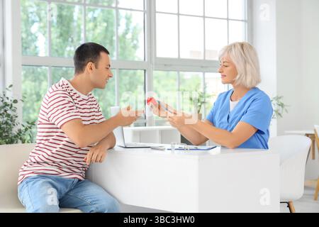 Endokrinologin zeigt Schilddrüsenmodell beim Mann in der Klinik Stockfoto