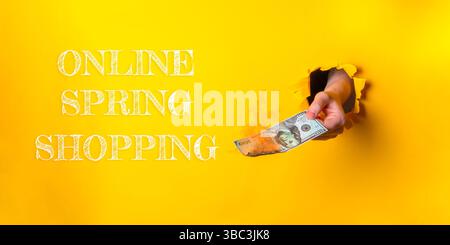 Halten Sie einen Schein vor einem gelben Hintergrund mit den Worten Online Spring Shopping unten Stockfoto