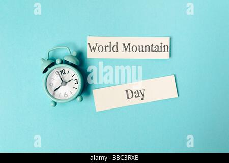 Uhr mit den Händen auf die Zahlen 3 und 9. Ein Stück Papier mit dem Wort World Mountain drauf Stockfoto