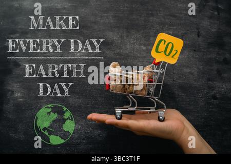 Hand hält einen Einkaufswagen mit einem Schild mit der Aufschrift Make Every Day Earth Day. Konzept, kleine Schritte zu Unternehmen, um positive Auswirkungen auf die Umwelt zu erzielen Stockfoto