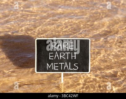 Symbol für Seltenerdmetalle. Konzeptworte seltene Metalle auf wunderschöner Tafel. Wunderschöner Hintergrund mit rotem Meerwasser. Gewerbe- und Seltenerdmetalle Stockfoto