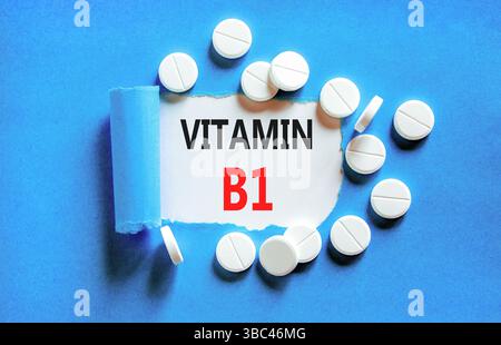 Vitamin B1-Symbol. Konzeptworte Vitamin B1 auf wunderschönem Weißbuch. Weiße Tabletten. Wunderschöner blauer Hintergrund. Medizinischer gesunder Lebensstil Vitami Stockfoto