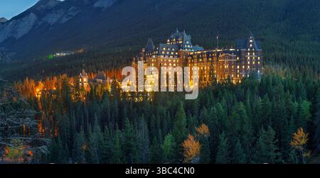 Das Fairmont Banff Springs Hotel, das „Schloss in den Rockies“, leuchtet im Abendlicht, umgeben von dichtem Wald. Stockfoto