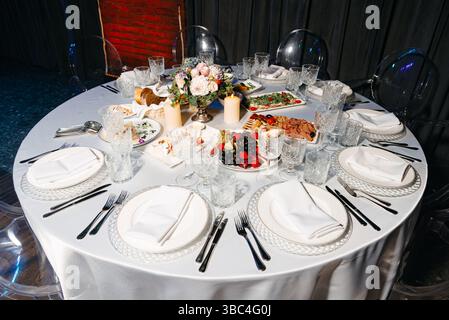 Schön gestalteter Banketttisch für Gäste mit verschiedenen Vorspeisen, frischem Obst, Wurstwaren und elegantem Geschirr. Stockfoto