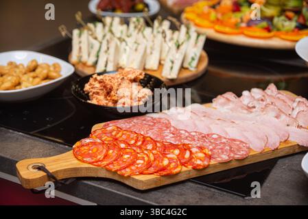 Verschiedene Aufschnitt-Wurstwaren einschließlich Salami, Chorizo und Schinken auf einem Holzbrett für ein Buffet oder eine Party. Stockfoto