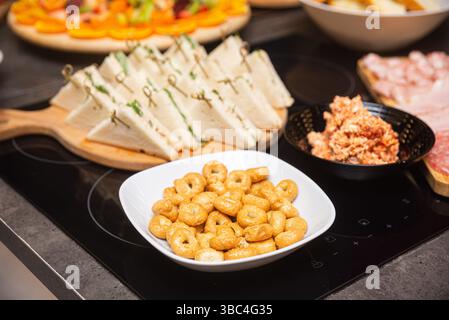 Verschiedene italienische Vorspeisen, darunter Taralli, cremige Sandwiches und Wurstwaren, die auf einem Buffet zum Aperitif oder zur Party serviert werden. Stockfoto