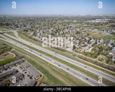 Autobahn mit vielen Autos und ein paar Trucks. Die Straße ist von Häusern und einigen Gebäuden umgeben Stockfoto