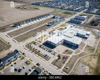 Großer Schulcampus mit Parkplatz und Spielplatz. Der Parkplatz ist voll mit Autos und der Spielplatz ist leer Stockfoto
