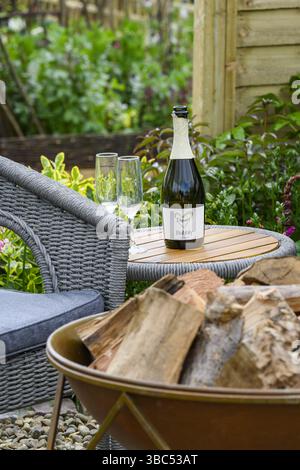 Butterfly Garden - Terrasse in Nahaufnahme, grauer Sitz (Sit Relax), 2 leere Gläser, offene Flasche - Harrogate Spring Flower Show 2025, Yorkshire England UK Stockfoto