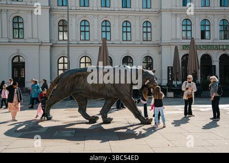 Oslo, Norwegen - 13. April 2024: Menschen und Kinder interagieren an einem sonnigen Tag in Norwegen mit der berühmten bronzenen Tigerstatue in der Nähe des Osloer Hauptbahnhofs. Stockfoto
