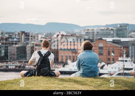 Oslo, Norwegen - 13. April 2024: Ein Paar sitzt und entspannt an einem Aussichtspunkt auf einem Hügel in der Nähe des Osloer Hafens. Stockfoto