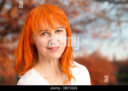 Porträt einer rothaarigen Frau vor einer orangen Herbstlandschaft Stockfoto