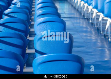 Eine Anordnung von hellblauen Stadionsitzen aus der Nähe, die Organisation und Einheitlichkeit zeigen und die architektonische Struktur und das Purpo hervorheben Stockfoto